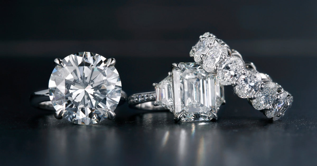 Three diamond rings include a round solitaire, an emerald-cut stone with side accents, and a line of round diamonds.