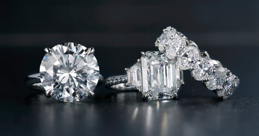 Three diamond rings include a round solitaire, an emerald-cut stone with side accents, and a line of round diamonds.